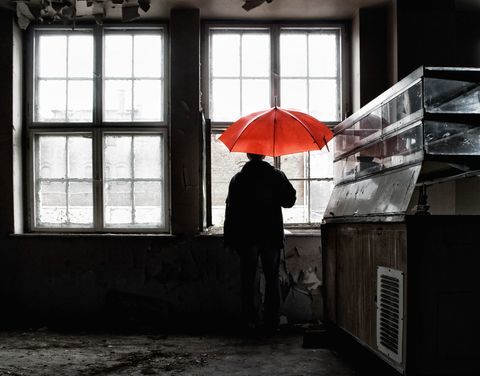 Човек држи црвени кишобран отворен у згради