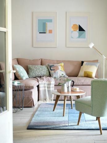 ружичаста софа зелена фотеља и плави ругарт урамљени графички отисци и јастуци са модерним уметничким дизајном дају упечатљив контраст пригушеној палети пастелних боја