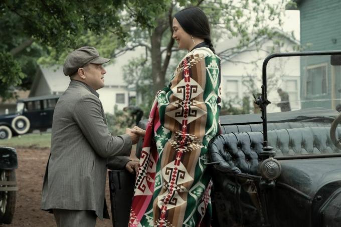 мушкарац и жена који стоје поред аутомобила са украшеним шалом