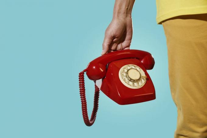 човек са старим црвеним телефоном у руци