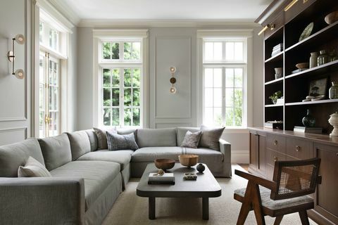 породична соба, дрвена полица за књиге, лајсне од круне, светиљке, сиви кауч на развлачење