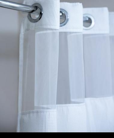 бела завеса за туширање која виси на хромираној шипки завеса за туширање