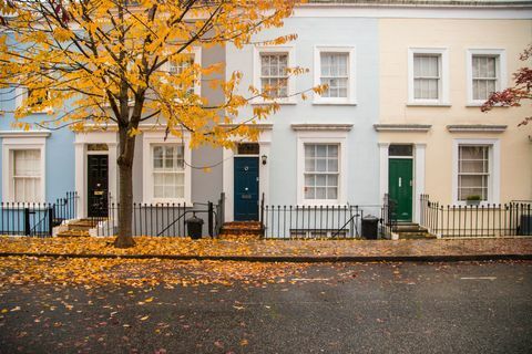 Комшије куће Ноттинг Хилл са фасадом пастелне боје лепе композиције без аутомобила и дрвећем с јесењим лишћем на земљи у граду Лондону. Велика Британија, Европа.
